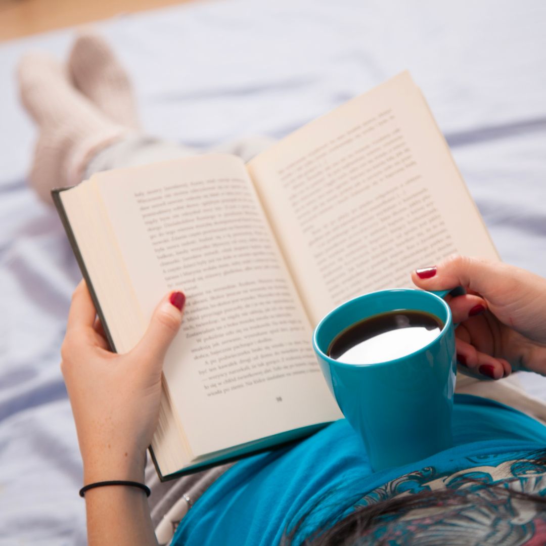 Woman reading a book and holding cup of coffee