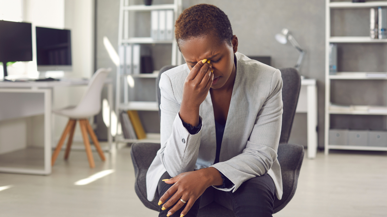 women sitting in office chair, hands on face looking stressed