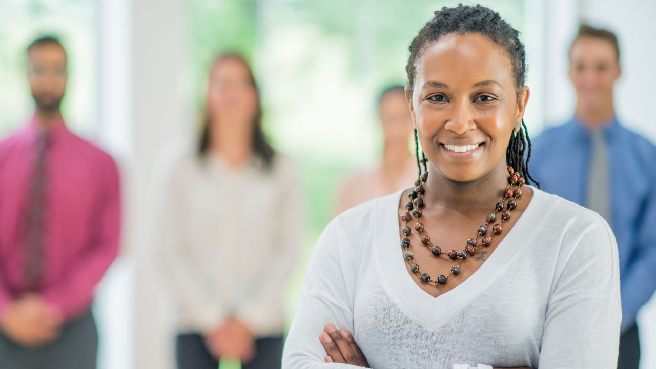 Black women standing in front of a group of peers; she exemplifies authentic leadership